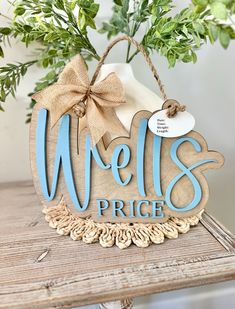 a wooden sign that says wells price hanging on a table with greenery in the background