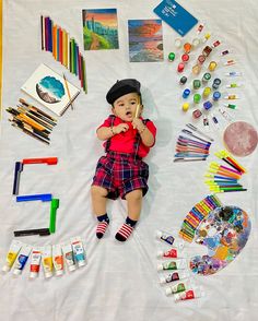 a young child laying on top of a white sheet covered in art supplies and crafts