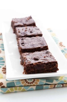 chocolate brownies on a white plate sitting on a table