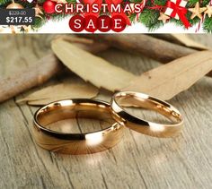 two gold wedding rings sitting on top of a wooden table next to leaves and twigs