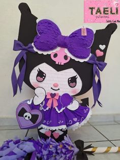 a paper doll with purple and black hair holding a heart shaped item in her hands