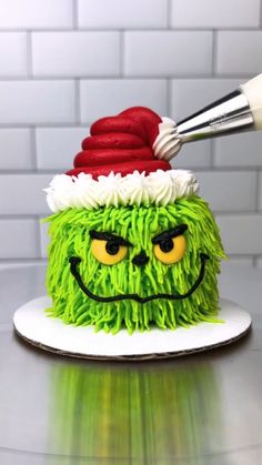 a cake with green frosting and a red santa hat on it's head