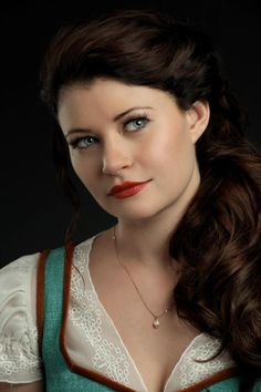 a woman with long hair and blue eyes wearing a green dress is posing for the camera