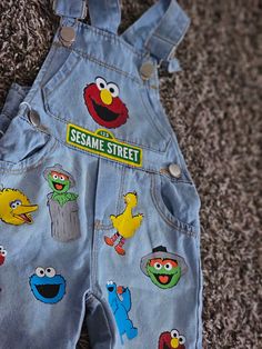 the sesame street denim overalls are decorated with cartoon characters