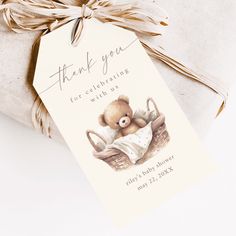 a baby shower gift tag with a teddy bear in a basket on it's side