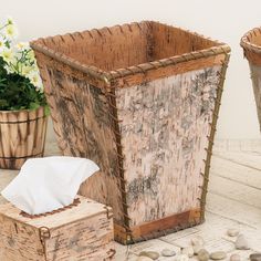 two wooden baskets with tissue paper in them on a table next to rocks and flowers