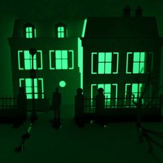 two people standing in front of a green lit house