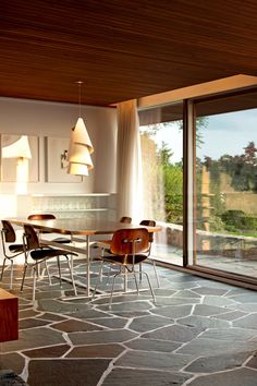 a dining room with large windows and stone flooring