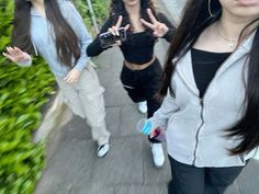 three young women walking down a sidewalk with their hands up in the air while making peace signs