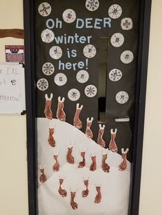 a classroom door decorated with paper snowmen and reindeers for winter is here written on it