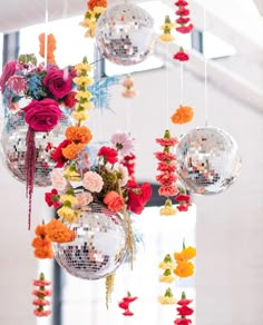 several disco balls hanging from the ceiling with flowers on them and decorations attached to it