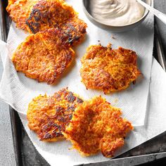 four crab cakes on a tray with dip