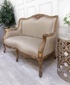 an ornately decorated chair sits next to a table with a potted plant on it