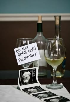 two wine glasses sitting on top of a table next to bottles and papers with pictures