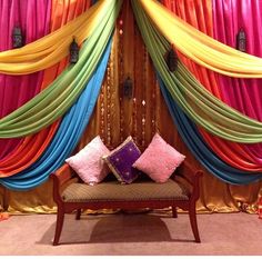 a couch sitting under a colorful drape with two pillows on it