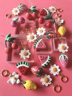 a collection of fruit and flower keychains on a pink surface