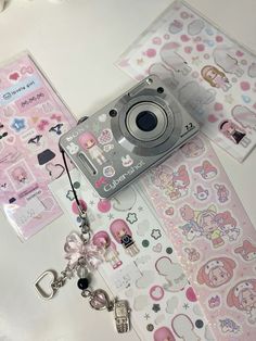 a camera sitting on top of a table next to some stickers and key chains