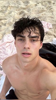 a shirtless young man laying on the beach