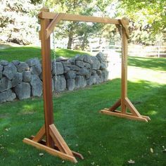 two wooden frames sitting on top of green grass next to a stone wall and trees