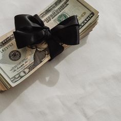 a stack of one hundred dollar bills tied with a black bow