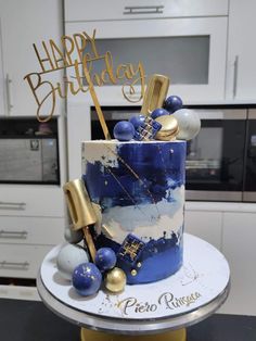 a blue and white birthday cake with gold decorations