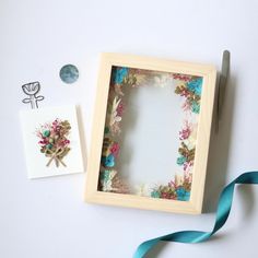 a box with some flowers on it next to a blue ribbon and other items that include scissors