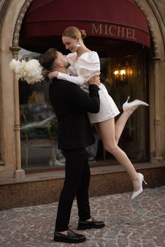 a man in a tuxedo is holding a woman on his back while she holds her