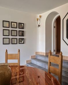 a dining room table with chairs and pictures on the wall above it in an arched doorway