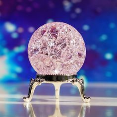 a crystal ball sitting on top of a metal stand in front of a blue and purple background