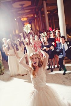 a woman in a white dress is posing for a photo with other people behind her