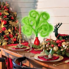 the table is set for christmas dinner with green decorations