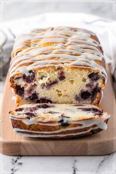 a loaf of lemon blueberry bread with icing on a cutting board next to a plate