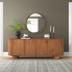 a living room with a large mirror on the wall next to a wooden sideboard