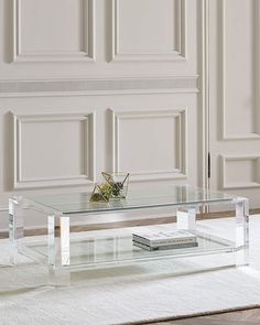 a glass coffee table sitting on top of a rug in front of a white wall