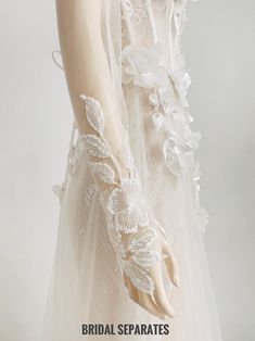 a white dress with flowers and lace on the sleeves is shown in front of a mannequin's head