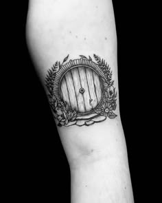 a black and white photo of a hobbot tattoo on the left arm with flowers around it