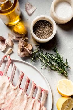 raw meat on a plate next to garlic, lemons and pepper sprigs