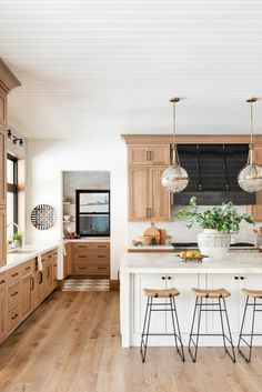 a large kitchen with wooden cabinets and white counter tops, two stools at the island