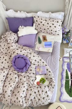 a bed with purple and white comforters on it