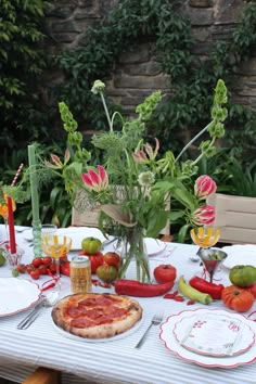 a table topped with a pizza covered in toppings next to a vase filled with flowers