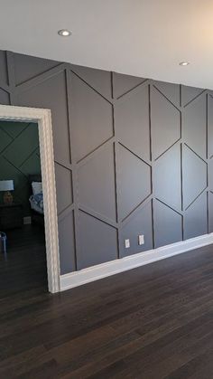 an empty room with wood flooring and gray wall covering it's back walls