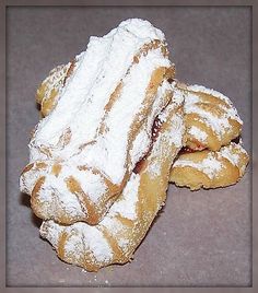 three powdered sugar covered donuts stacked on top of each other in front of a gray background