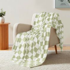 a green and white blanket sitting on top of a chair next to a potted plant