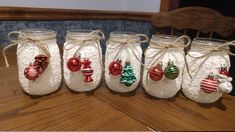 four mason jars filled with ornaments on top of a wooden table