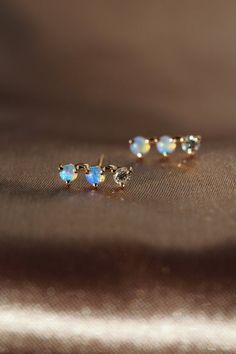 two opal earrings sitting on top of a cloth