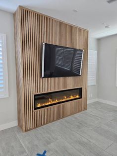 a tv mounted on the side of a wooden wall in a living room with tile flooring