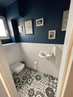 a white toilet sitting next to a sink in a bathroom under pictures on the wall