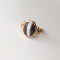 A vintage 9 carat yellow gold banded Agate ring. This charming piece has a really great shape and is a very simple setting. The precious stone forms in volcanic cavities, making Banded Agate a beautiful example of Nature's capabilities. CONDITION: Wear consistent with age and use. Please see photos for more detail. BAND WIDTH: 1.5mm SETTING SIZE: 12mm x 10mm SETTING AND STONE HEIGHT: 4mm RING SIZE: UK: M | US: 6 1/4 WEIGHT: 2.6g (UZZ) Banded Agate, Agate Ring, Solitaire Ring, Gold Bands, Precious Stones, Agate, Gemstone Rings, Jewelry Rings, Ring Size