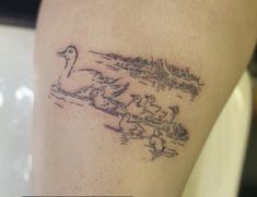 a tattoo on the leg of a woman with ducks swimming in water and trees behind her