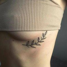 a woman's stomach with a small leaf tattoo on her left side ribcage